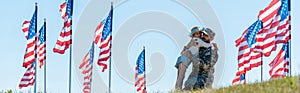 Shot of kid hugging father in military uniform near american flags
