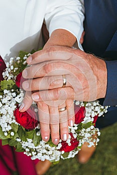 Shot of the loving married couple showing their hands and matching rings in front of the bouquet.