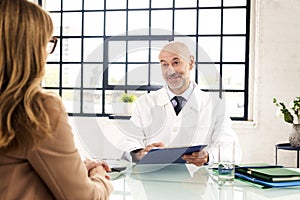 Shot of male doctor sitting at desk and consulting with her female patient in the hospital