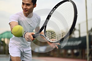 Shot of male tennis player hitting ball with racket. Sport, fitness, training and active life concept