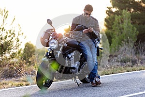 Man biker talking on the phone to the insurance of his motorcycle after having suffered a breakdown on the road photo