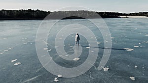 Shot of man skating on a frozen lake on a sunny winter day taken on a drone