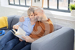 Shot of a married couple reading a book together and relaxing on the sofa at home