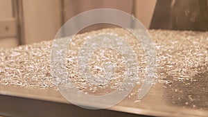 Shot of metal shavings flying off from working angle grinder on steel table.