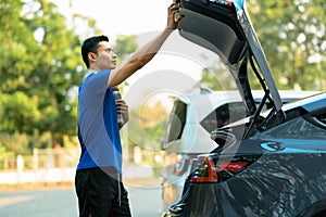 Shot of millennial asian man in a sporty outfit standing near her car while going to the gym. Fitness lifestyle concept