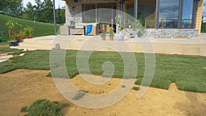 Shot of a modern house and the big backyard being renovated with tiles of grass.