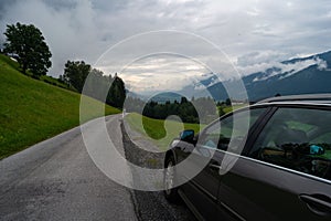 Shot near car of Mittersill mountains with thick forest and low clouds sitting on the peak