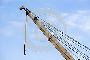 Shot of an old, rusty port crane preparing to lift cargo in ship on overcast sky background