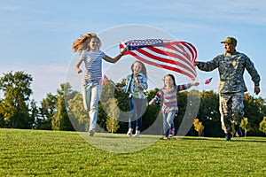 Shot of patriotic family running with flag.