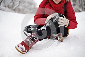 Shot of person during falling in snowy winter park. Woman slip on the icy path, fell, injury knee and sitting in the snow
