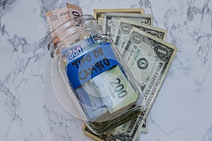 Shot of pesos and dollars in a jar with a [Tipo De Cambio - exchange rate] sign on it on the table photo