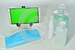 Shot of a phone, medical spirts and a face mask on a table