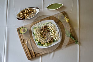 shot of a plate with salads cheese cubics , avocado on a wooden board and guacamole and bread cubics