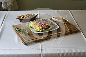 Shot of a plate with salads, cheese cubics, and ham on a wooden board and bread cubics
