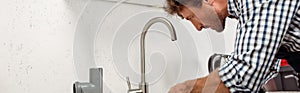 Shot of plumber fixing kitchen faucet