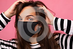 Shot portrait of young brunette attractive woman wearing mediacal face mask  over background wall. Protection