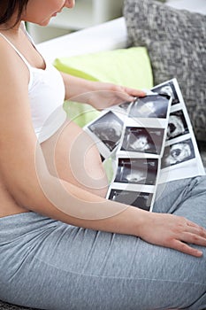 A shot of a pregnant woman looking her child's ultrasound pictu