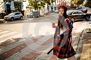 Shot of pretty young asian woman crossing the street while holding the smartphone and looking sideways.