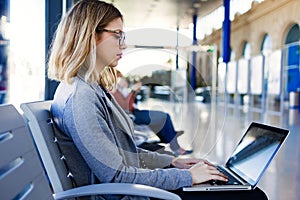 Pretty young business woman using her laptop in the train station.