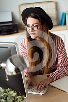 Pretty young business woman working with her laptop in the office.