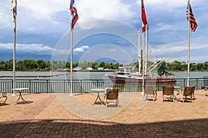 A shot of a red and white fishing boat sailing down the Savannah river with 4 flags flying on the banks of the river