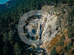 Shot of river falling down through the rocky mountains surrounded by evergreen forest