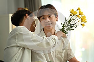 Shot of romantic asian man giving a bunch of flowers to his boyfriend. LGBTQ people lifestyle and love emotion