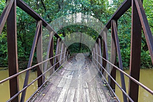 A shot of a rust colored iron bridge covered in fallen leaves over the brown waters of the Chattahoochee silky brown river