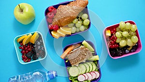 Shot of school lunchboxes with various healthy nutritious meals on blue background