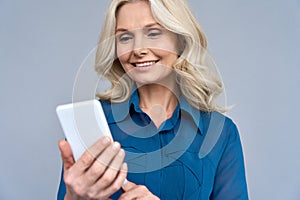 Shot of senior 50s aged blonde female manager using phone isolated on gray