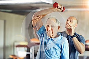 Not letting age affect his agility. Shot of a senior man working out with the help of a trainer.