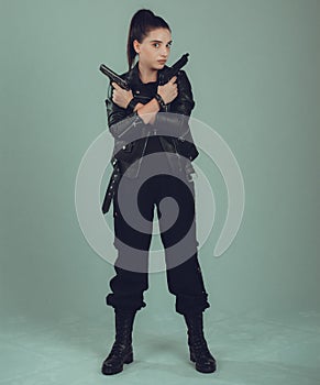 Shot of a sexy military woman posing with guns,in a black jacket