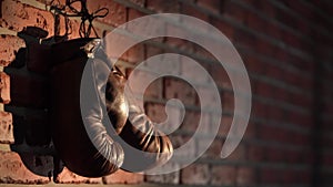 The shot shows a close up of a loft style brick wall with a nail nailed on it. A man then hangs up brown, boxing gloves