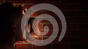 The shot shows a close up of a loft style brick wall with a nail nailed on it. A man then hangs up brown, boxing gloves