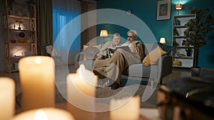 The shot shows a close up of a vinyl record player with a record spinning. In the background, an elderly couple are