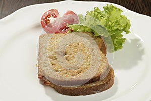 A shot of a slice of bread with a tomatoe and some salad on the side