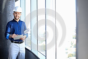 Shot of smiling male architect wearing hardhat and inspecting new building