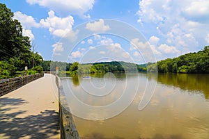 A shot of the still waters of the Chattahoochee river with lush green trees reflecting off the water with a boardwalk