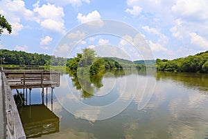 A shot of the still waters of the Chattahoochee river with lush green trees reflecting off the water with a boardwalk