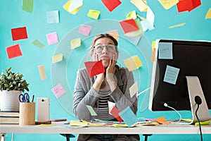 Stressed young business woman looking up surrounded by post-its in the office