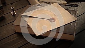 Shot of the table with old paper envelope. Vintage letter envelope laying on the old book sealed with wax stamp, feather