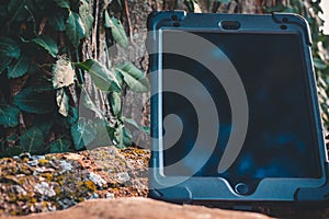 Shot of a tablet left propped up against a tree