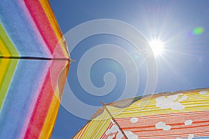 shot taken under a multicolor green blue red yellow orange umbrella against the perfect blue sky with sun