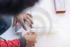 Shot of technician hands take measurements with a metal ruler on a iron pole and mark the required length