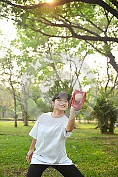 Shot of teenage Asian girl wearing leather glove playing baseball at public park