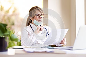 Shot of thinking female doctor sitting at office desk photo