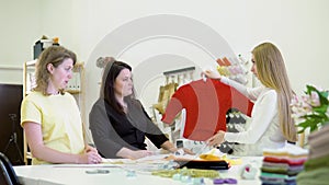 Shot of three fashion designers working and deciding details of new collection of clothes in the sewing workshop