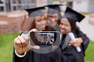 Memories of monumental moments. Shot of three female graduates taking a picture of themselves on a phone.