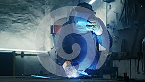 shot of a tired worker in a factory. steel structure welding, making homemade armor plate by professional worker using