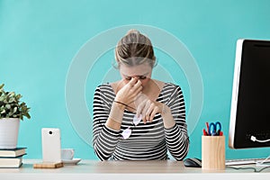 Tired young business woman having headache while working with computer in the office